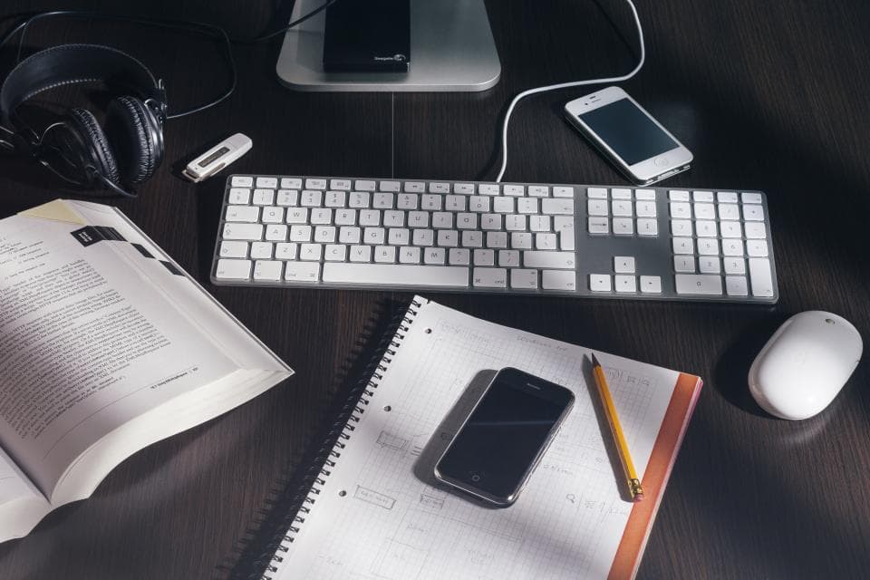 A tidy desk with a notebook, printed checklist, pen, and laptop.